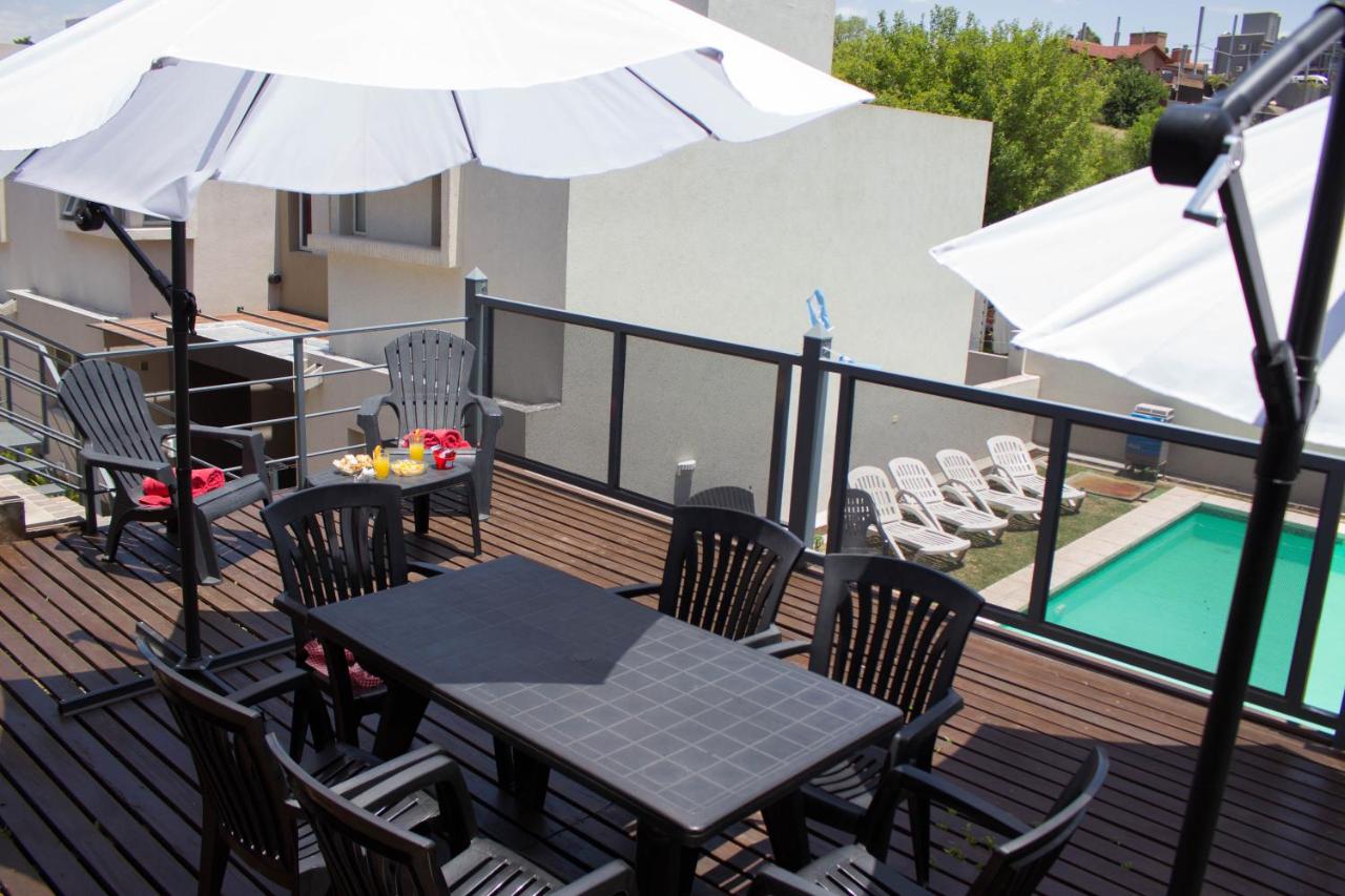 Terraza con mesa, sombrillas y vista a la pileta